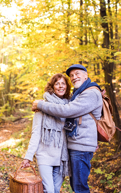 happy couple in the woods during autumn holding a picnic basket life insurance bentonville ak
